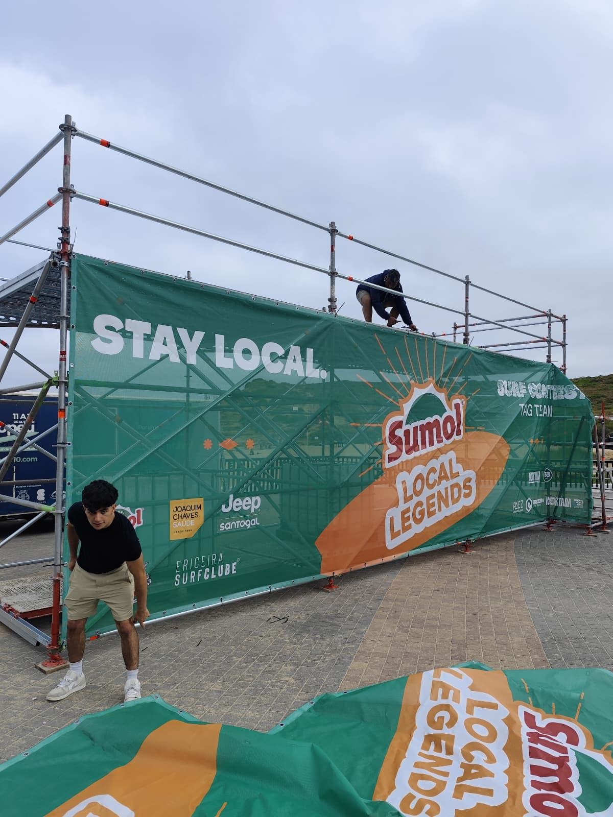 Trabalhador a colocar a lona publicitária na estrutura de andaime