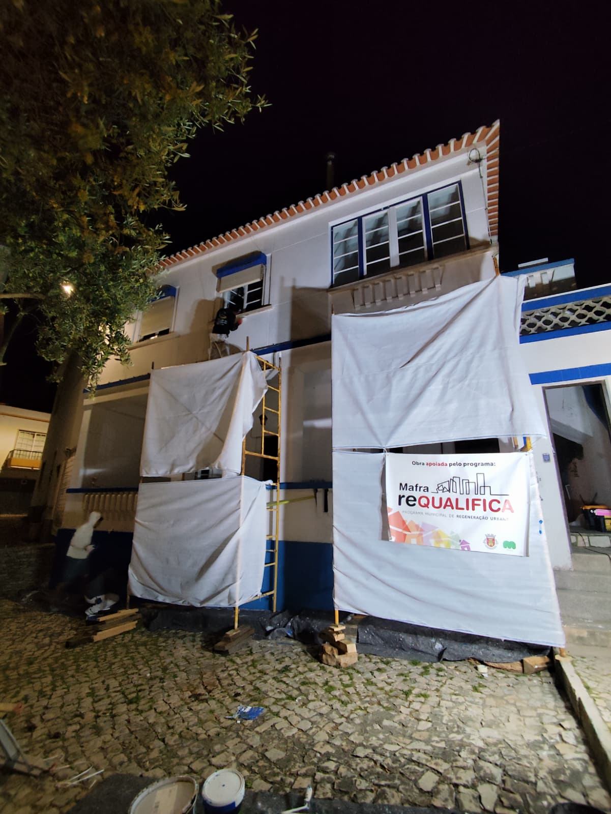 Fachada preparada à noite com andaime e lonas de proteção