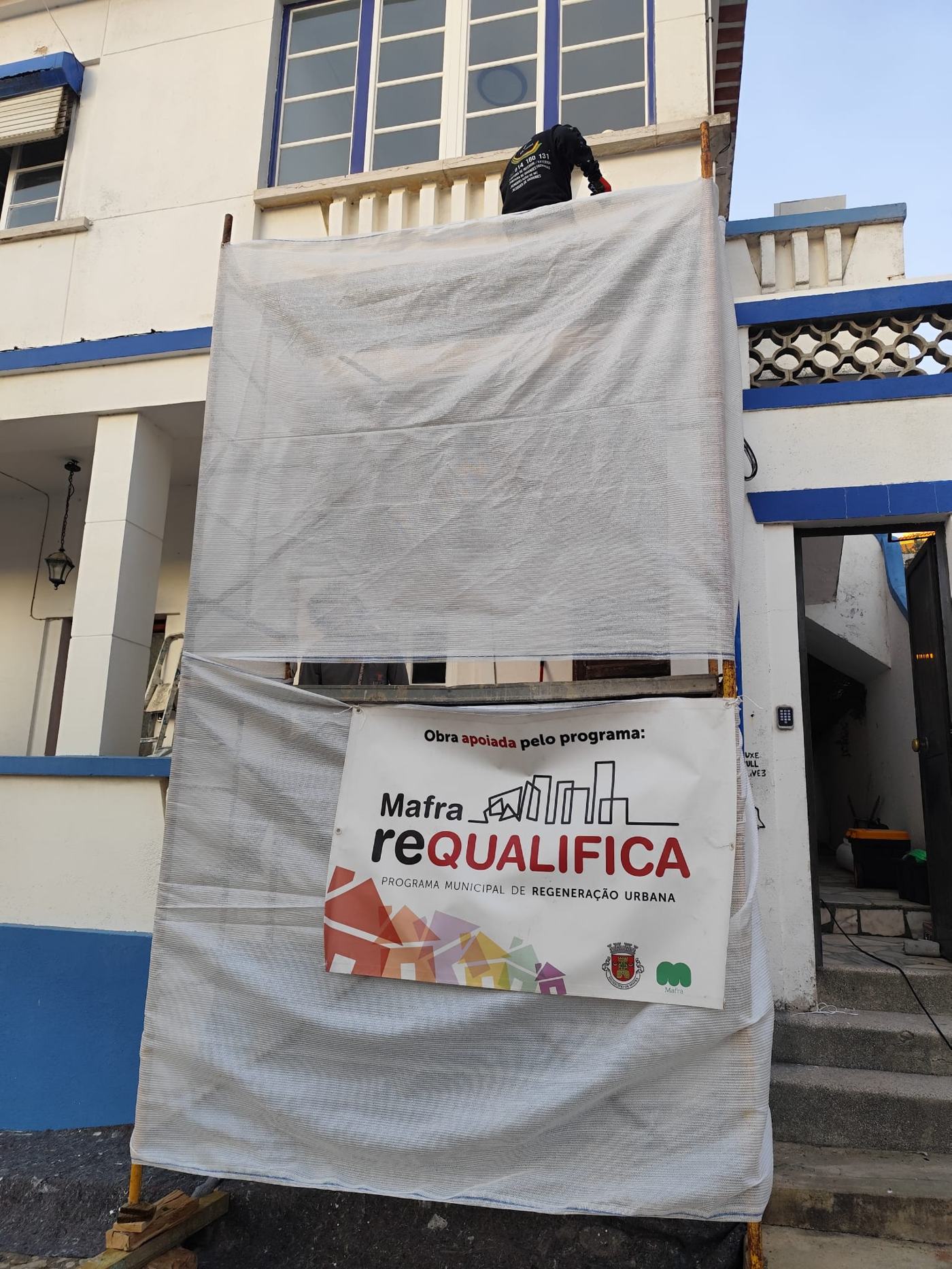 Pormenor do andaime com lonas de proteção e faixa do programa Mafra Requalifica