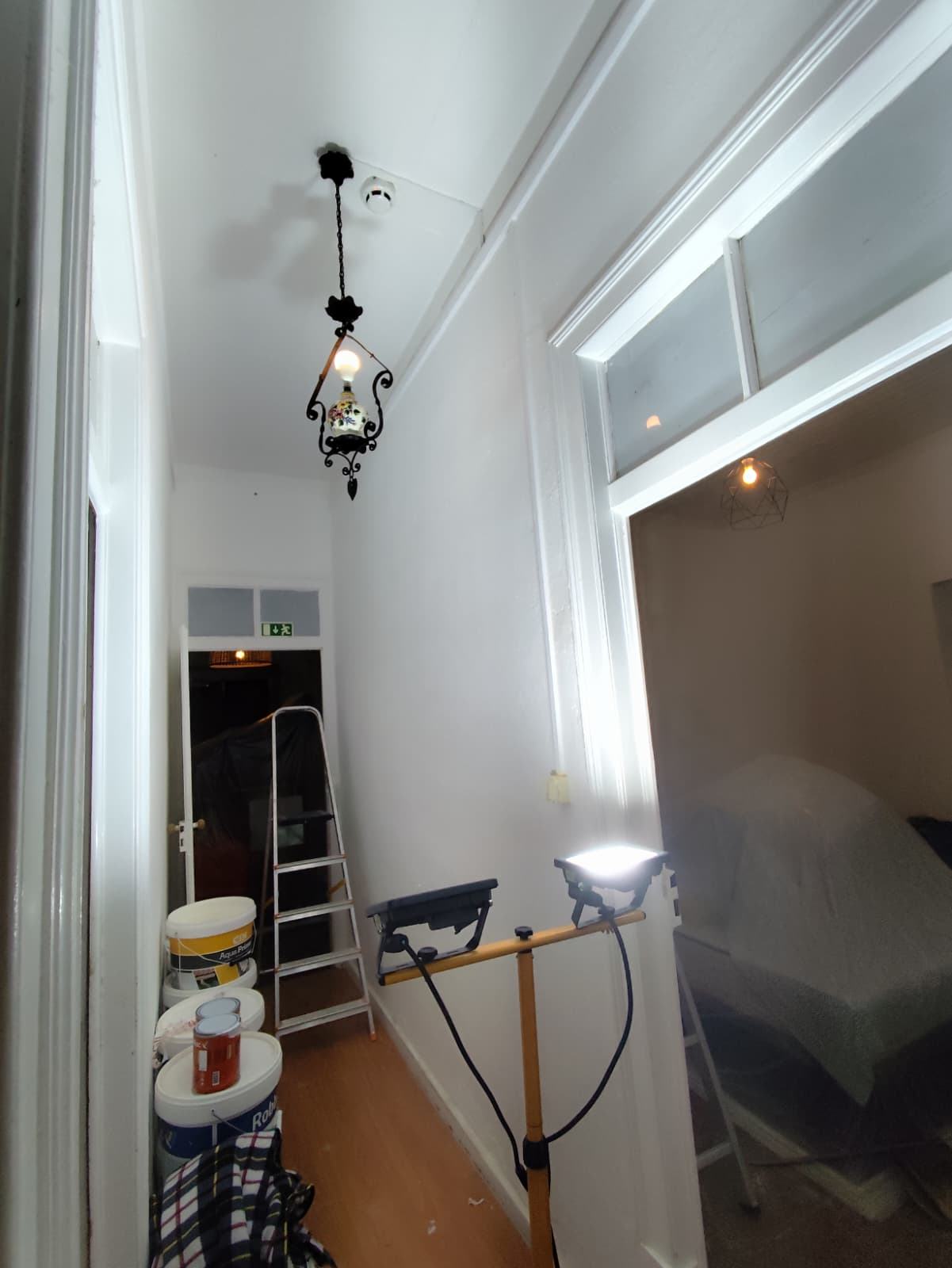 Corredor interior preparado para pintura, com latas de tinta e escadote