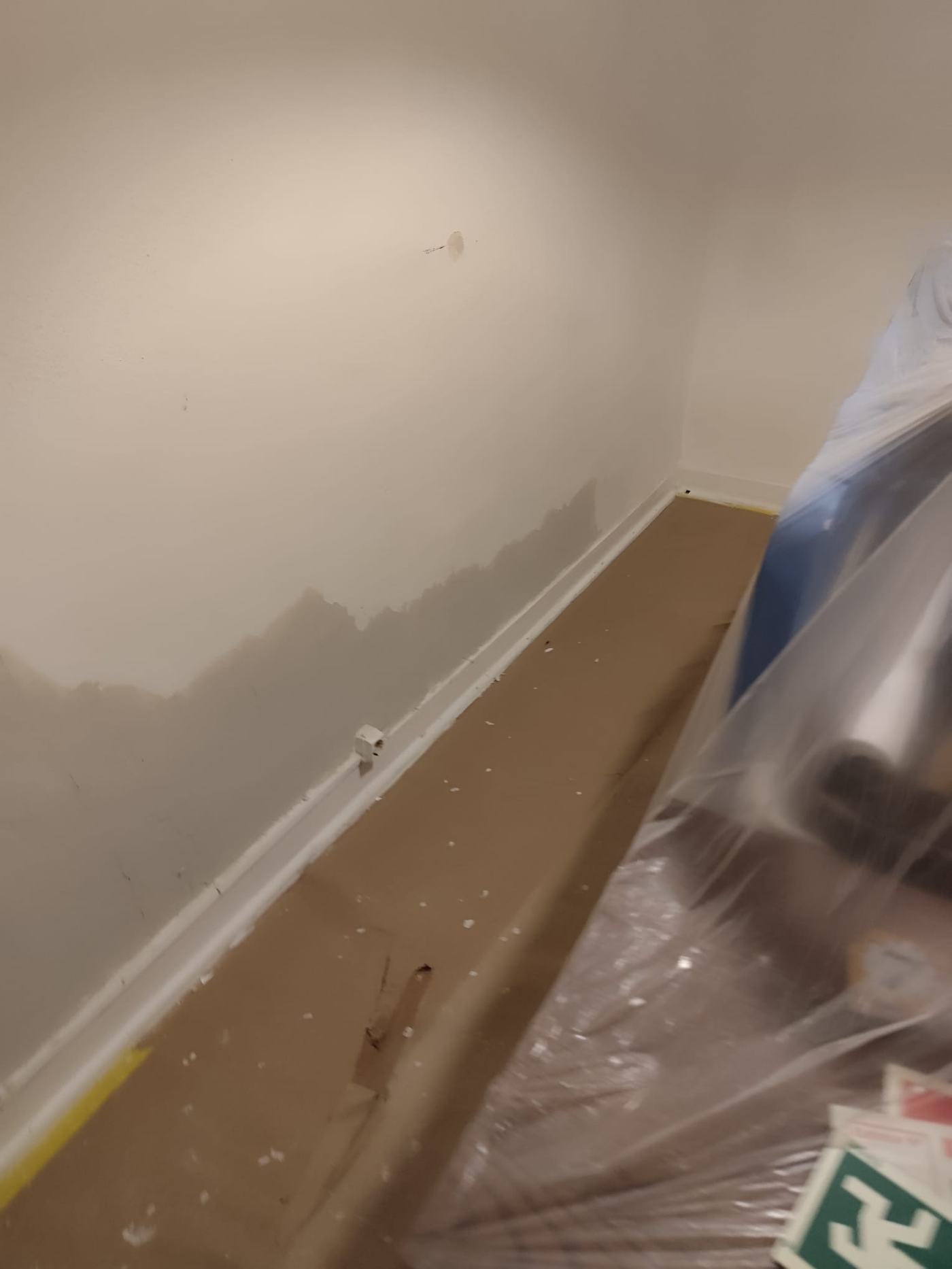 Parede com reparação de fissuras antes da pintura, chão protegido com plástico