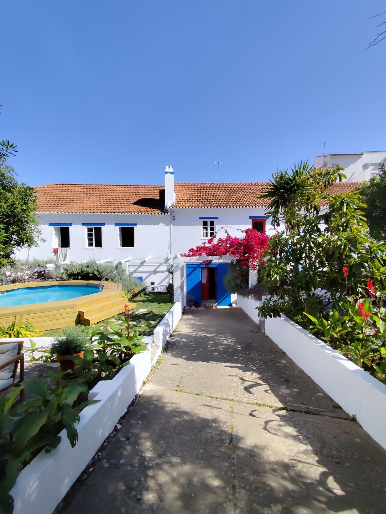 Casa com fachada pintada de branco e azul, jardim e piscina
