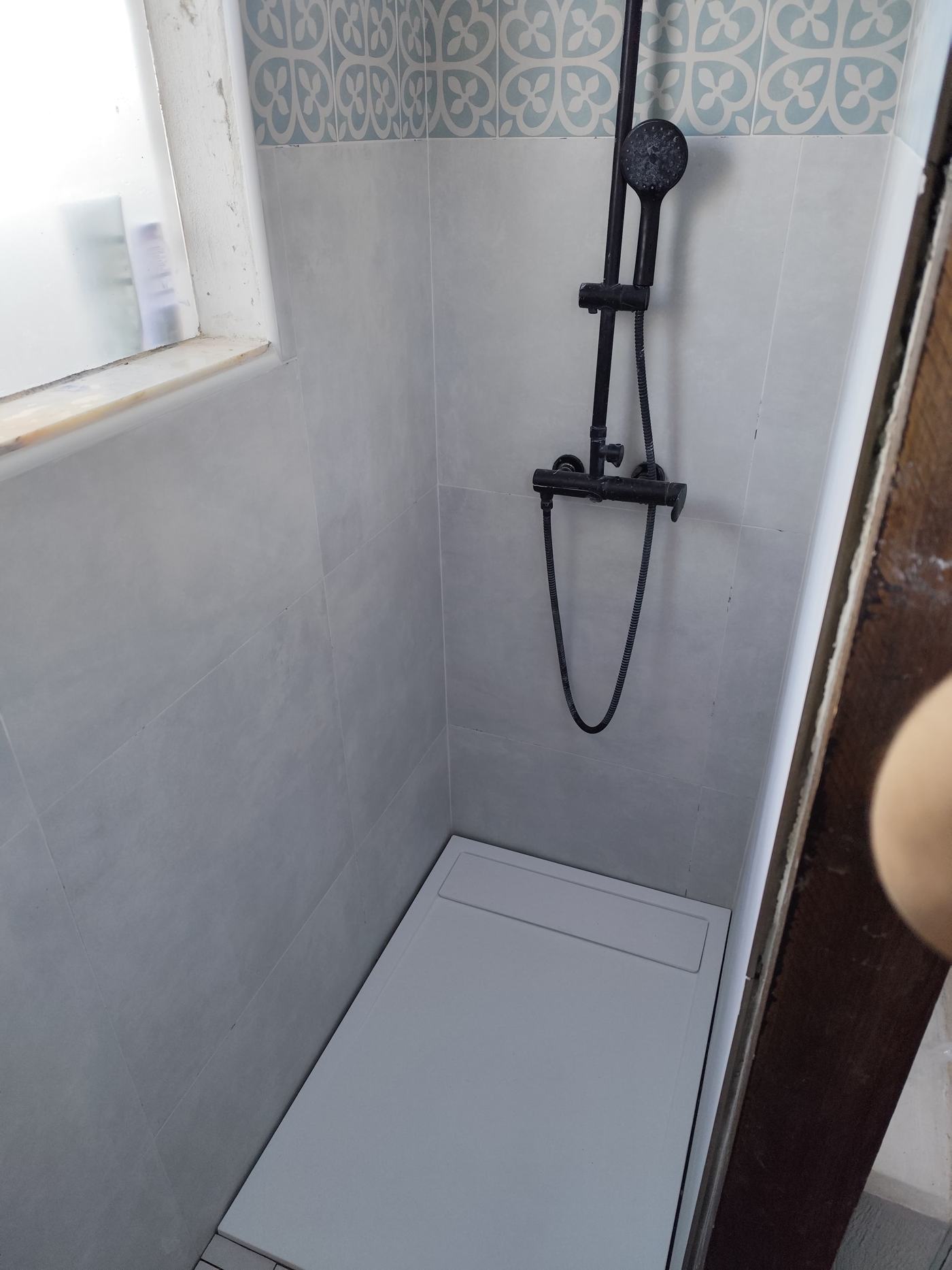 Casa de banho remodelada com azulejo decorativo e chuveiro preto