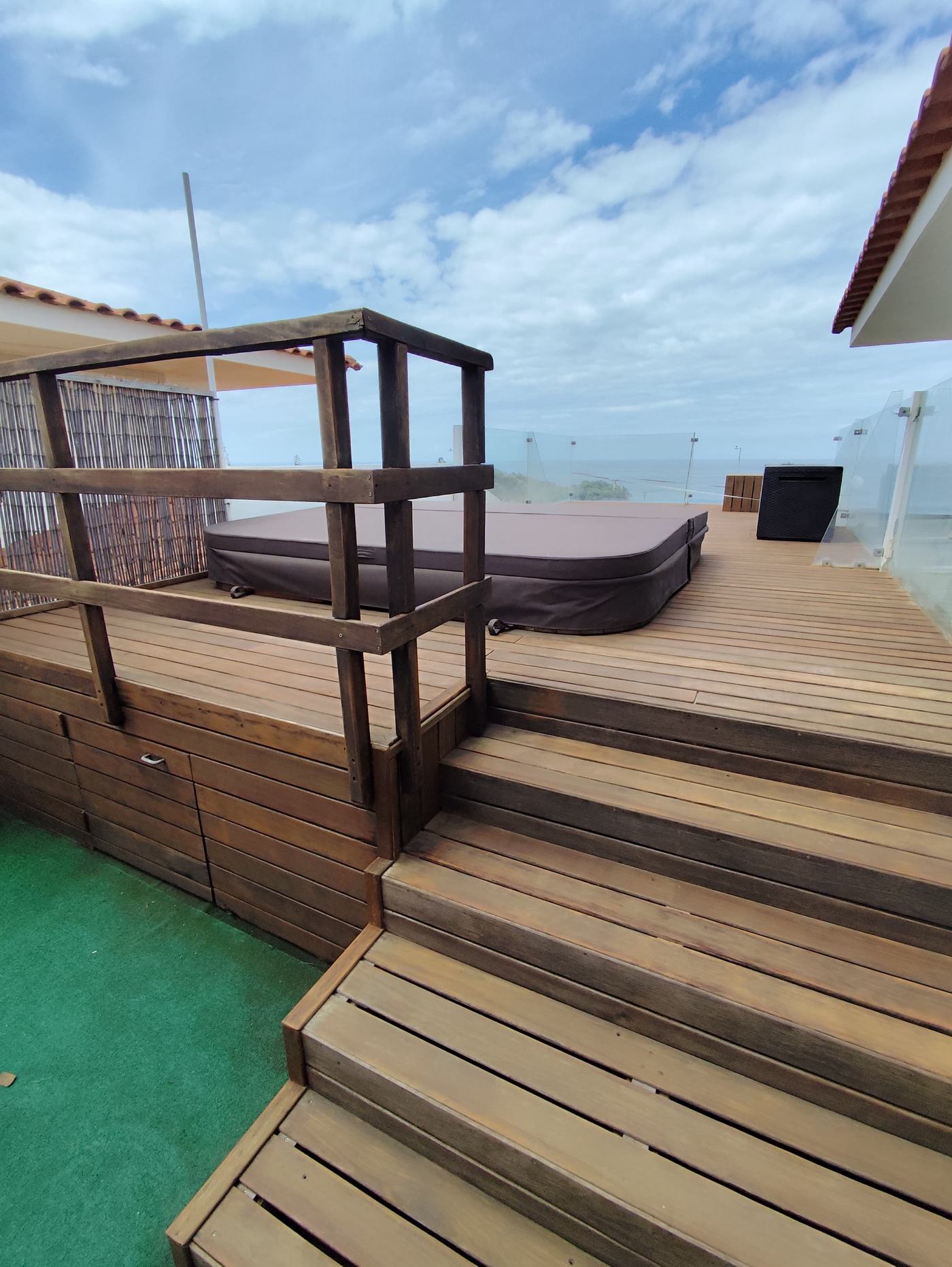 Deck de madeira envernizado a escuro, com vista para o mar