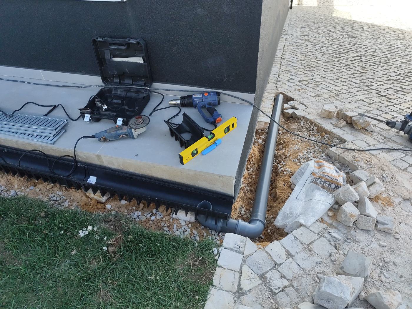Canal de drenagem instalado junto à fachada, com tubo de escoamento